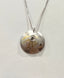 Silver necklace with a round pendant on a light gray background